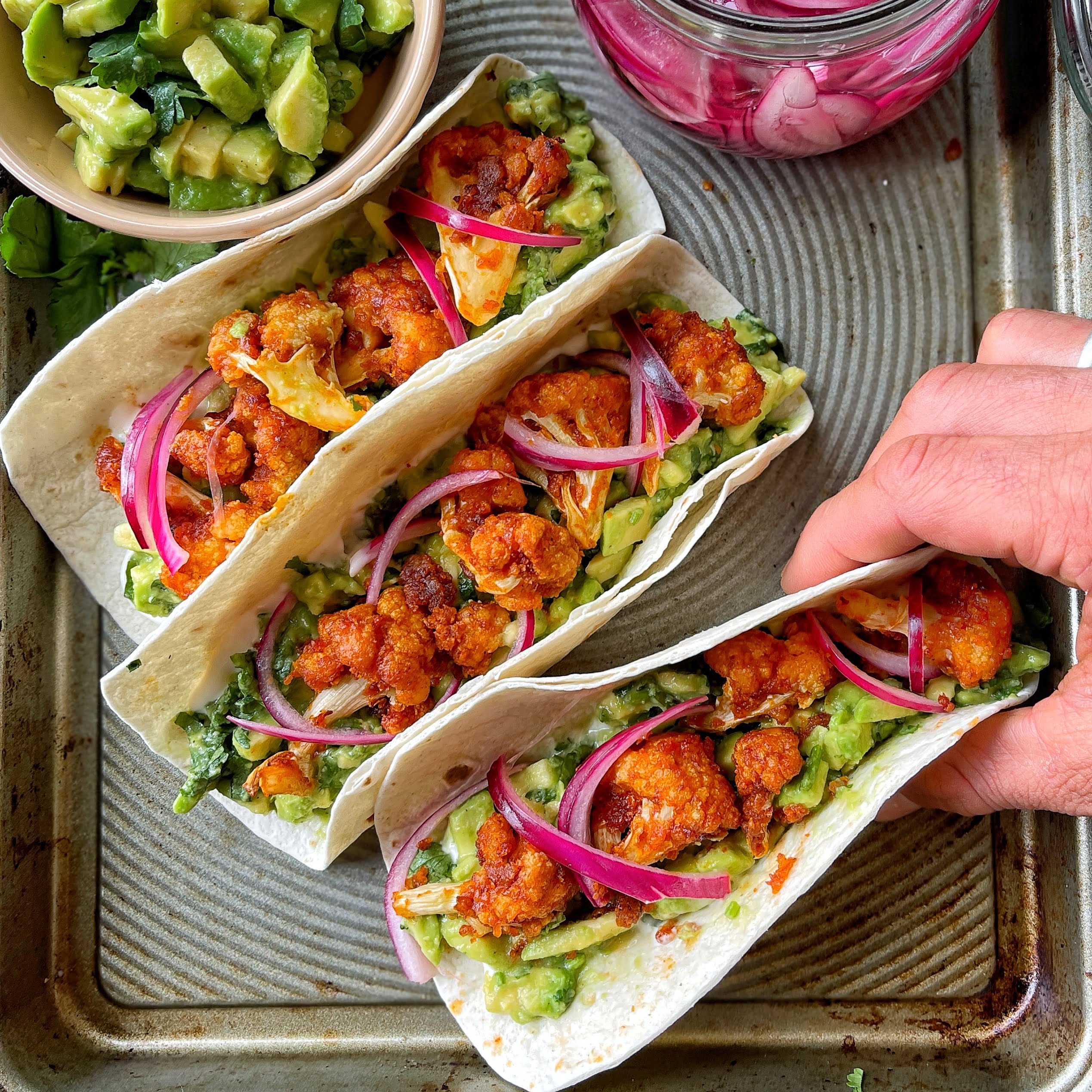 An image of Buffalo cauliflower wing tacos with quick pickled onion