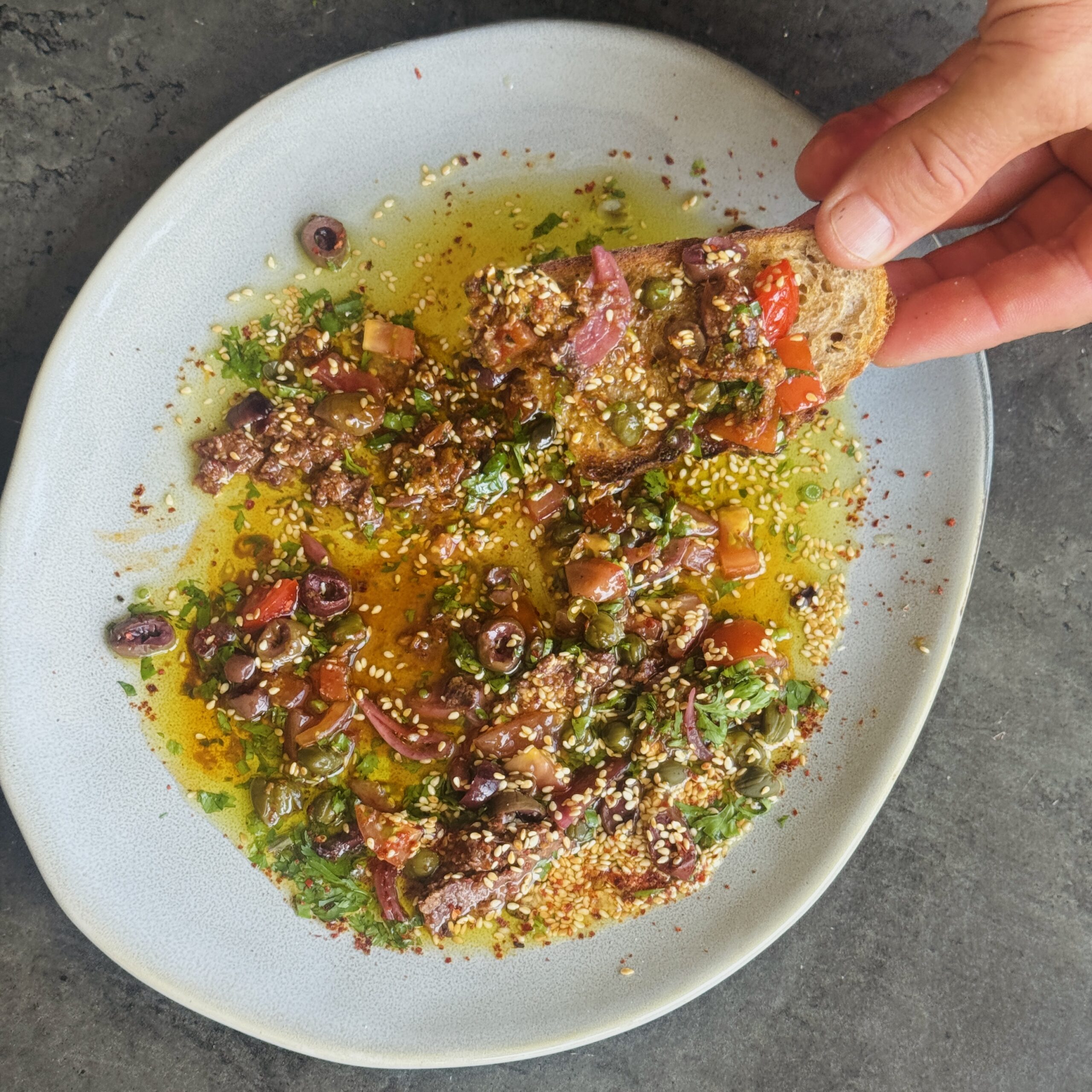 a photo of Loaded Olive Oil Dip with Herbs, Pesto, Tapenade & Capers